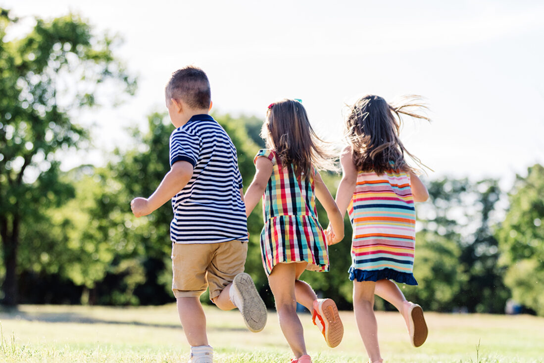 Three little friends running together in the park.