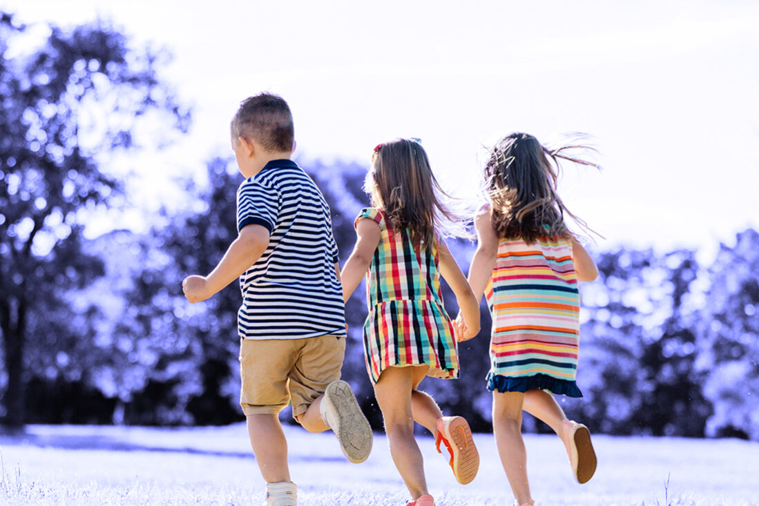 Three little friends running together in the park.